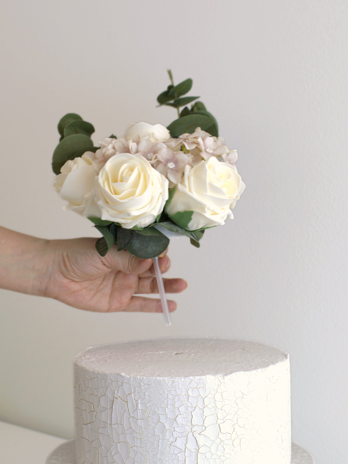 Floral topper placing on a cake, showcasing how easy it is to add instant elegance with high-quality artificial flowers for any special occasion.