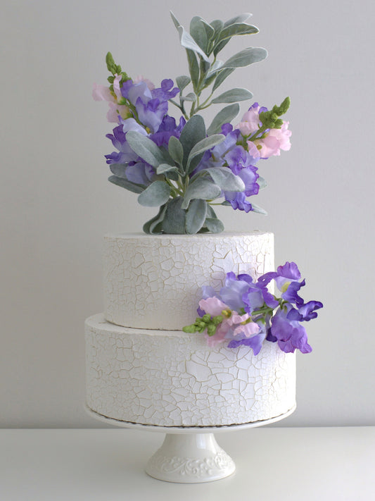 Set of Two Violet Floral Cake Toppers elegantly placed on a cake, featuring high-quality artificial flowers for weddings, birthdays, and special events.