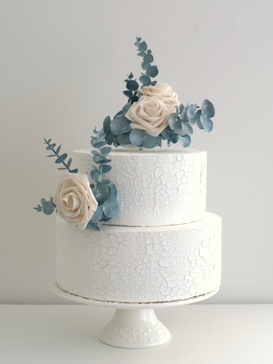 Rose and Eucalyptus Floral Cake Topper elegantly placed on a cake, featuring high-quality artificial flowers for weddings, birthdays, and special occasions.